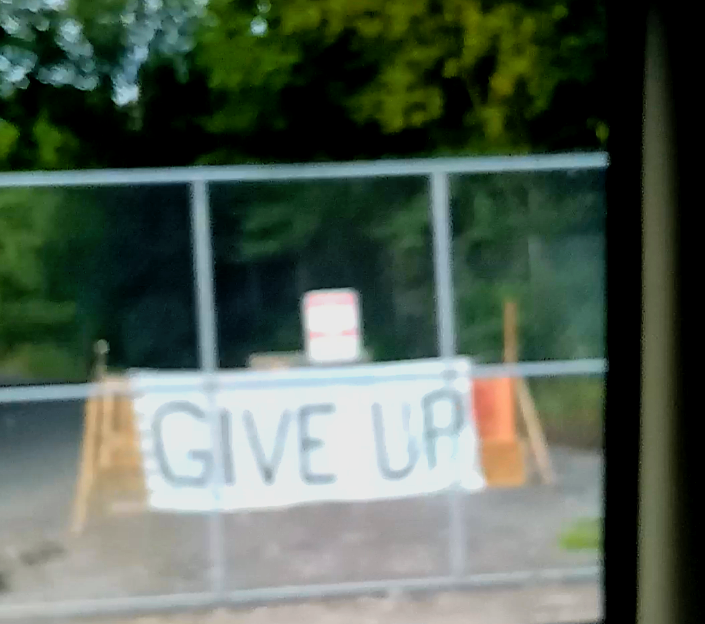 Barricaded gate with sign that read "Give Up"