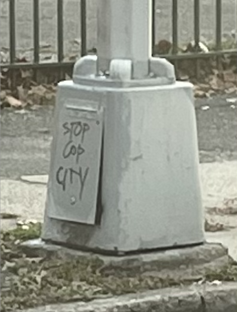 "STOP COP CITY" written in black paint marker on the base of a street light