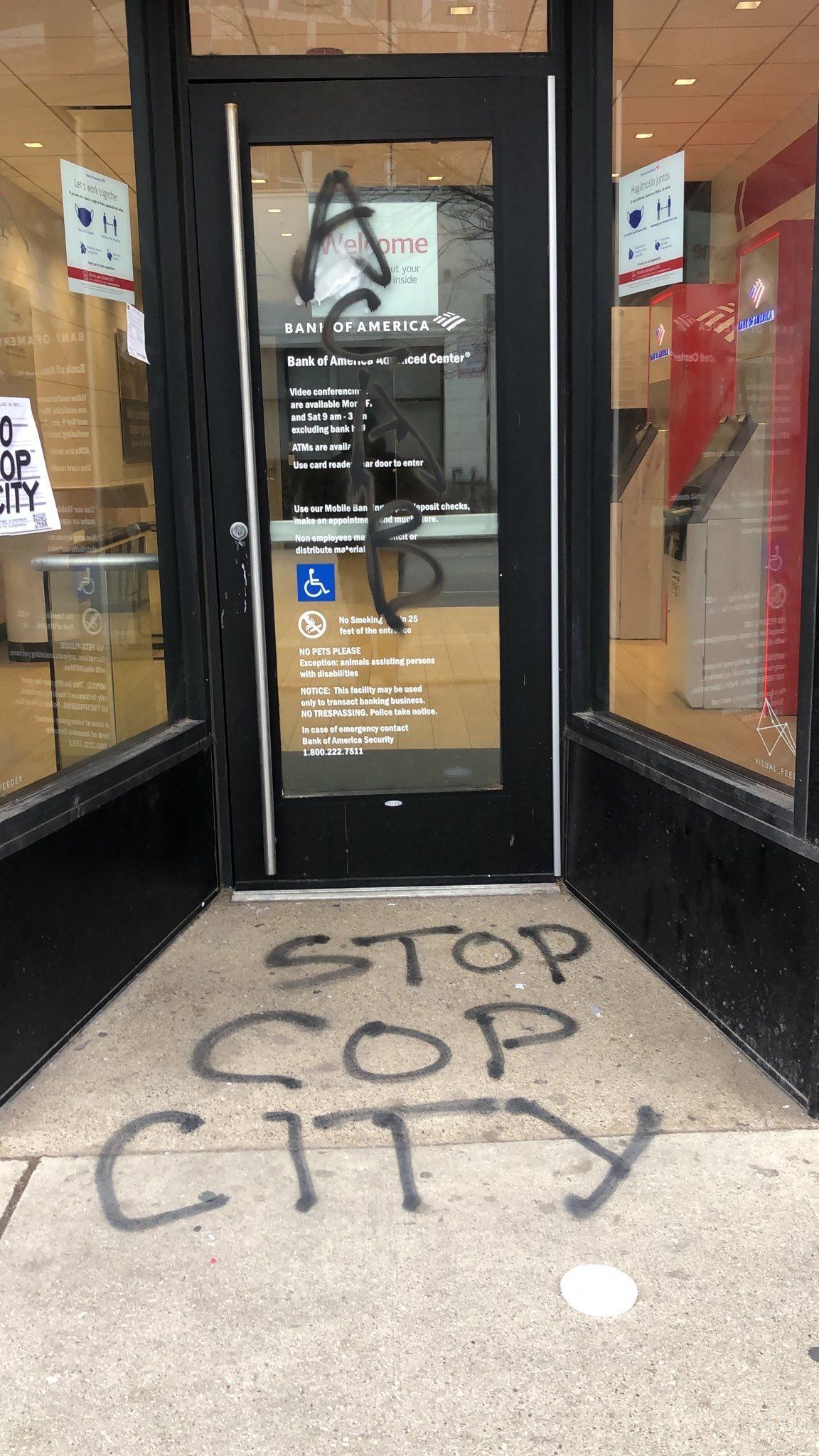 A door is covered in a tag that says "ACAB", and the ground says "NO COP CITY" in black spray paint.