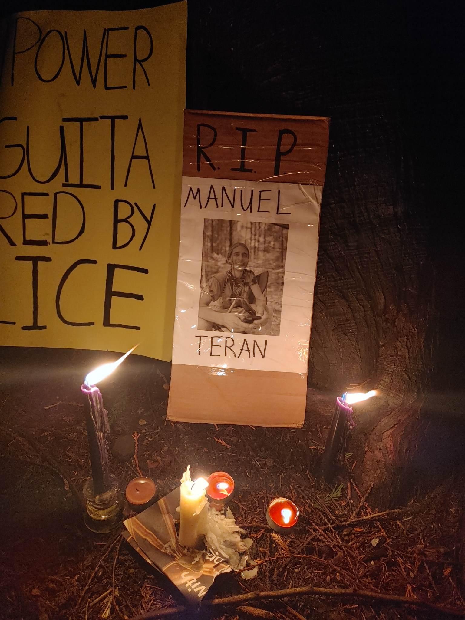 A picture of Tortuguita with the words RIP above it is lit by several vigil candles. Just out of frame is a sign upon which only the letters "GUITA- RED BY- ICE" are visible because the sign is out of frame.
