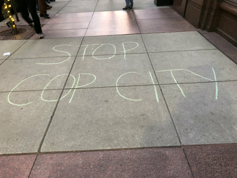 Onto a sidewalk, "STOP COP CITY" is tagged in green chalk.