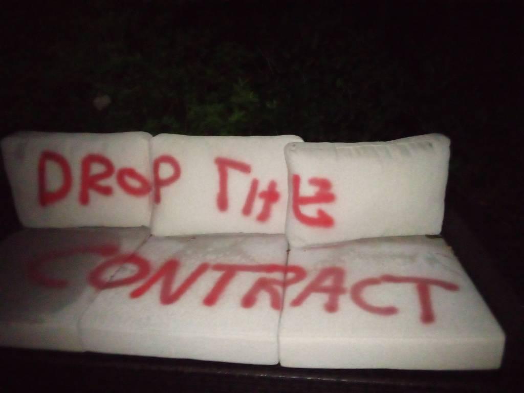 pool recliner with "DROP THE CONTRACT" spray painted on cushions